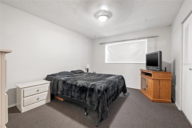 bedroom featuring ceiling fan, dark carpet, and a textured ceiling