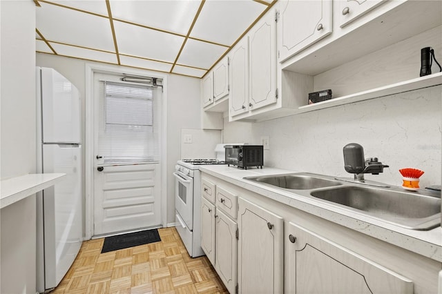 kitchen featuring tasteful backsplash, white appliances, light parquet floors, sink, and white cabinetry