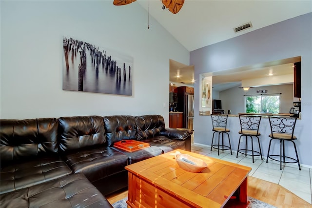 living room with ceiling fan, light tile patterned flooring, and lofted ceiling