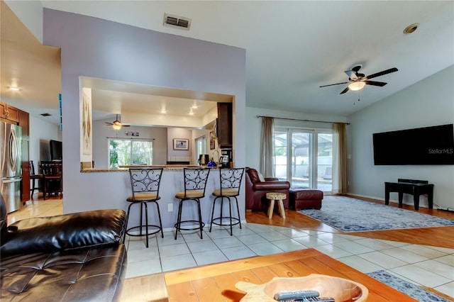 living room featuring ceiling fan, light tile patterned flooring, and vaulted ceiling