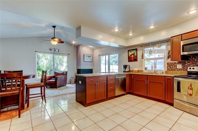 kitchen featuring ceiling fan, kitchen peninsula, vaulted ceiling, decorative backsplash, and appliances with stainless steel finishes