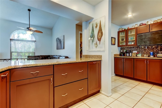 kitchen featuring decorative backsplash, ceiling fan, light stone counters, and light tile patterned floors