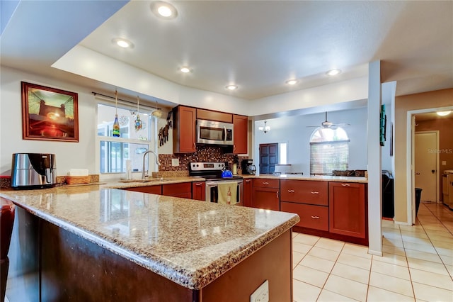 kitchen featuring kitchen peninsula, light stone countertops, stainless steel appliances, ceiling fan, and sink