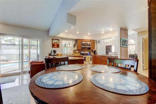 tiled dining space featuring sink and vaulted ceiling