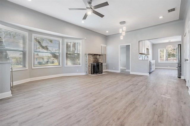 unfurnished living room featuring ceiling fan with notable chandelier and light hardwood / wood-style flooring