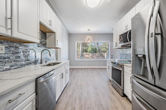 kitchen with pendant lighting, stainless steel appliances, white cabinetry, and sink