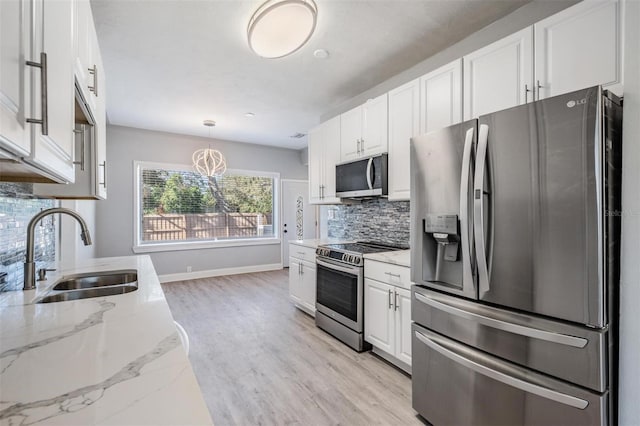 kitchen featuring white cabinetry, sink, stainless steel appliances, and decorative light fixtures