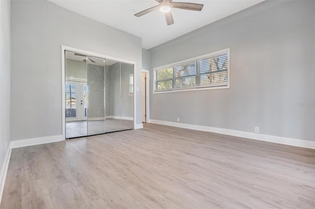 unfurnished bedroom with ceiling fan, a closet, french doors, and light wood-type flooring