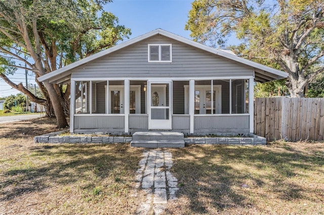 bungalow-style home featuring a sunroom and a front yard