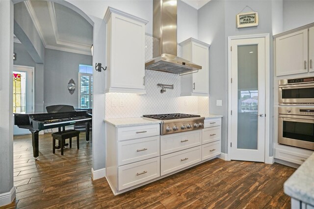 kitchen featuring dark hardwood / wood-style floors, stainless steel appliances, wall chimney exhaust hood, and white cabinetry