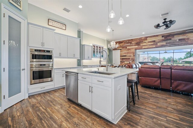 kitchen featuring sink, white cabinets, stainless steel appliances, and an island with sink