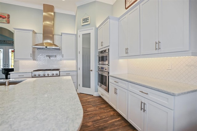 kitchen with exhaust hood, backsplash, dark hardwood / wood-style floors, white cabinetry, and appliances with stainless steel finishes