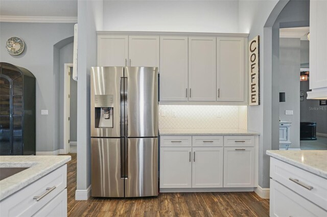 kitchen featuring light stone countertops, white cabinetry, dark hardwood / wood-style flooring, backsplash, and stainless steel fridge