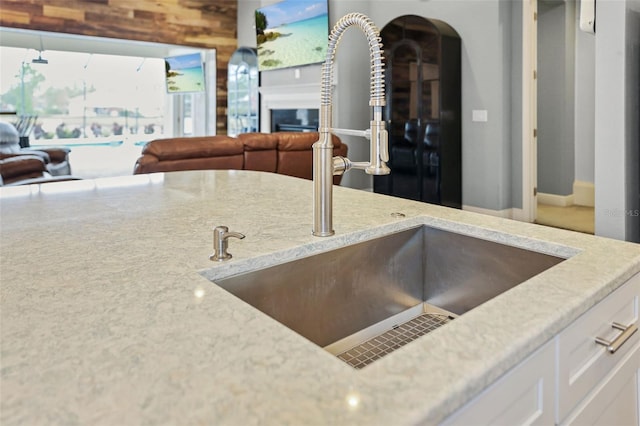 kitchen featuring white cabinets, light stone counters, and sink