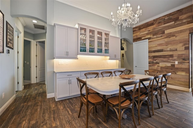 dining space featuring a chandelier, dark hardwood / wood-style flooring, wood walls, and ornamental molding