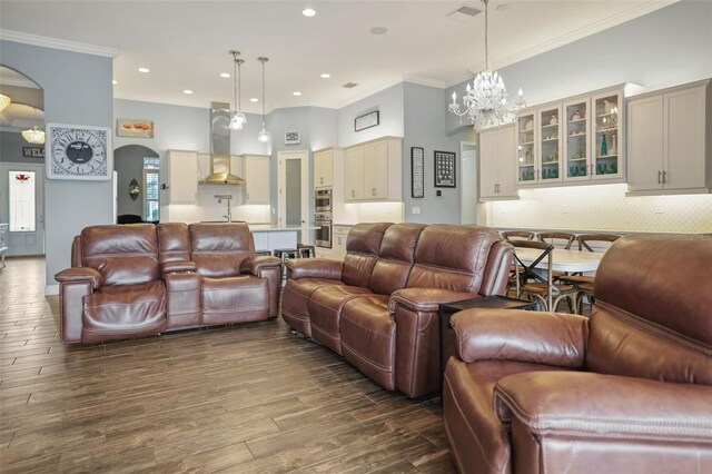 living room featuring dark hardwood / wood-style flooring, ornamental molding, and an inviting chandelier