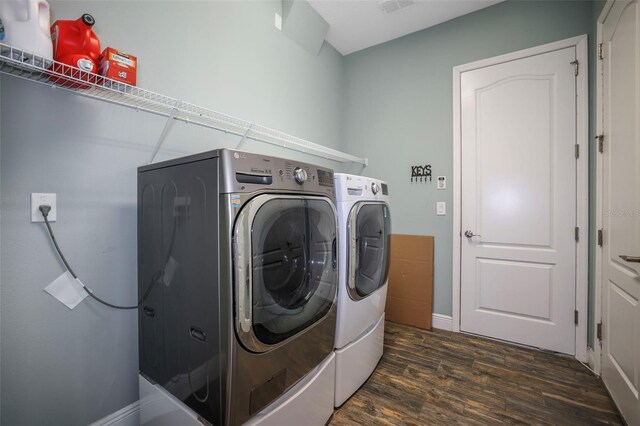 washroom featuring washing machine and dryer and dark wood-type flooring