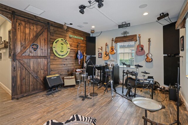 miscellaneous room with hardwood / wood-style flooring, a barn door, and wooden walls