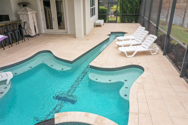 view of pool with glass enclosure, a patio area, a bar, and french doors