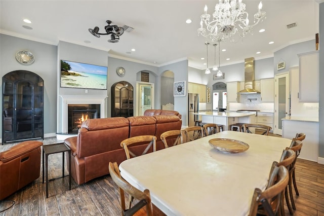 dining space featuring ceiling fan with notable chandelier, dark hardwood / wood-style floors, and crown molding