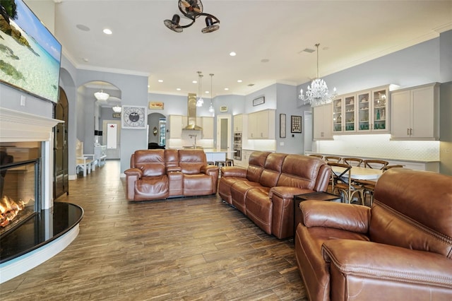 living room with dark hardwood / wood-style flooring, ornamental molding, and an inviting chandelier