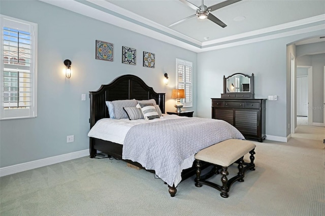 bedroom featuring ceiling fan, light carpet, multiple windows, and a raised ceiling