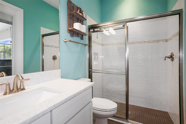 bathroom with walk in shower, vanity, and toilet