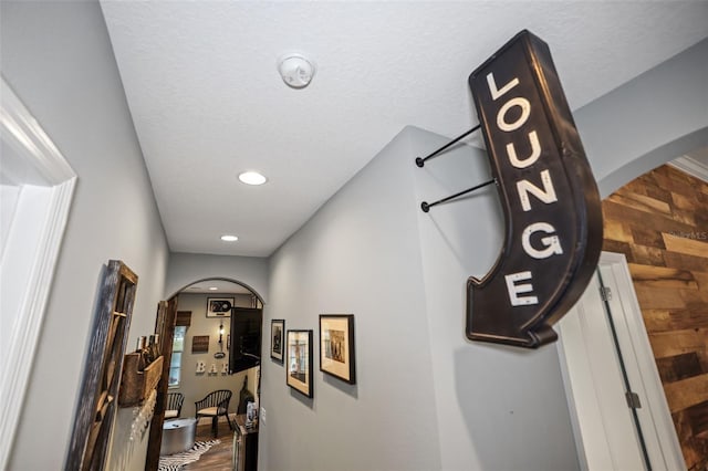 corridor with a textured ceiling and hardwood / wood-style floors