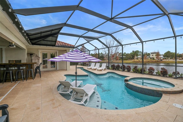 view of pool with glass enclosure, an in ground hot tub, exterior bar, a water view, and a patio