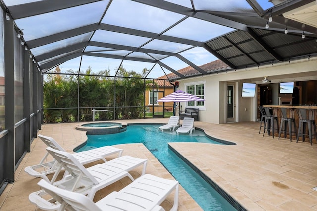 view of pool featuring glass enclosure, a patio area, a bar, and an in ground hot tub