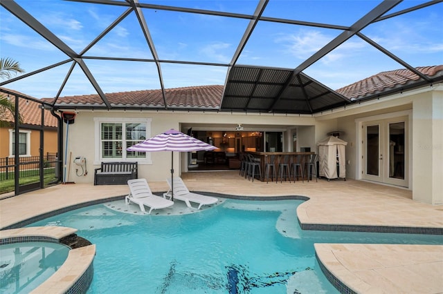 view of pool featuring a lanai, exterior bar, a patio area, and an in ground hot tub