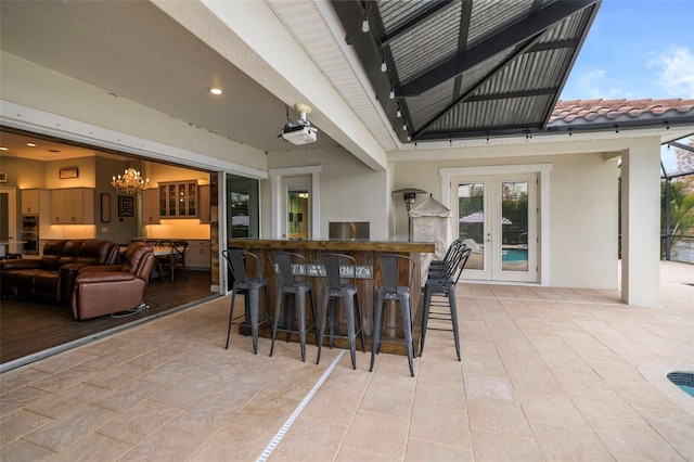 bar with light tile patterned floors, french doors, and an inviting chandelier