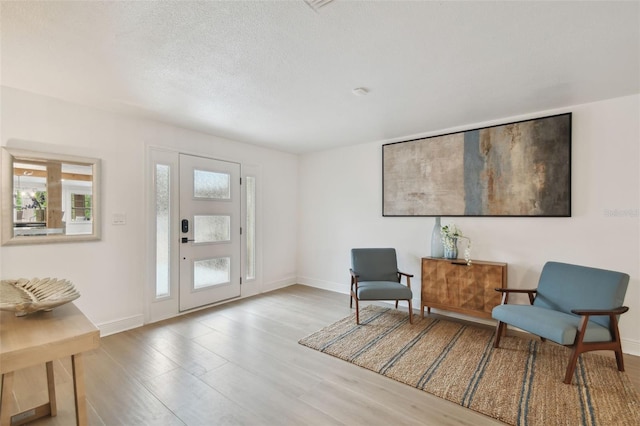 living area with a textured ceiling, light hardwood / wood-style flooring, and a healthy amount of sunlight