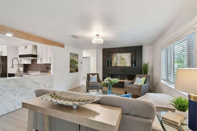 living room with a large fireplace, an inviting chandelier, and light hardwood / wood-style floors