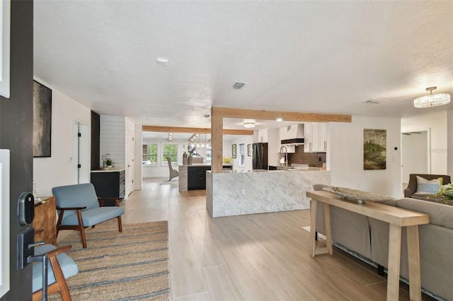 living room with light wood-type flooring, a chandelier, and a textured ceiling