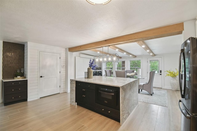 kitchen with pendant lighting, beam ceiling, light hardwood / wood-style floors, and black appliances