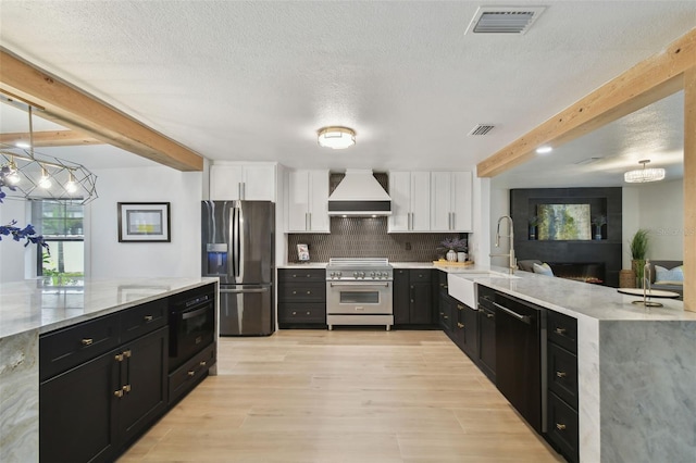 kitchen with premium range hood, appliances with stainless steel finishes, pendant lighting, white cabinets, and sink