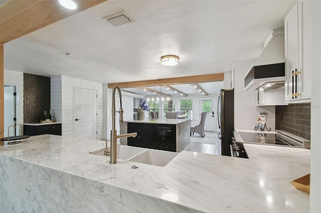 kitchen featuring range, white cabinetry, stainless steel fridge, kitchen peninsula, and beam ceiling