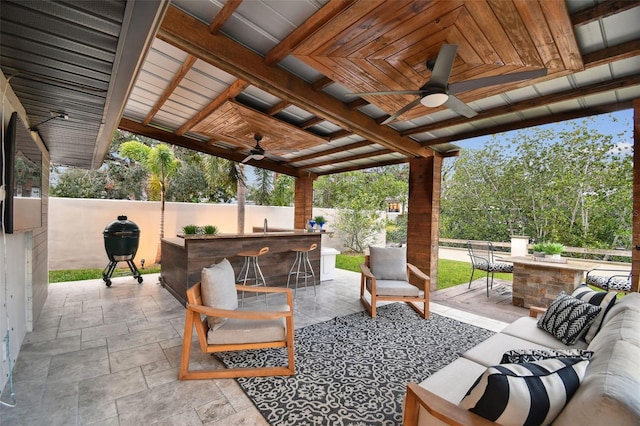 view of patio with ceiling fan, a bar, and an outdoor living space