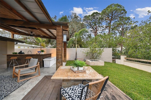 view of patio / terrace featuring ceiling fan, exterior bar, a wooden deck, and exterior kitchen