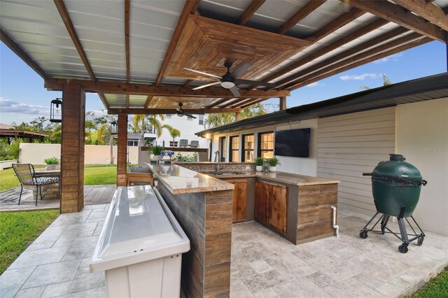 view of patio / terrace with ceiling fan, grilling area, exterior kitchen, and a wet bar