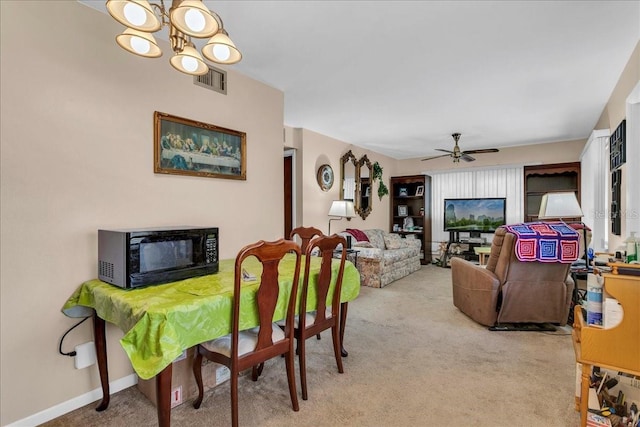 dining area featuring ceiling fan with notable chandelier and light carpet