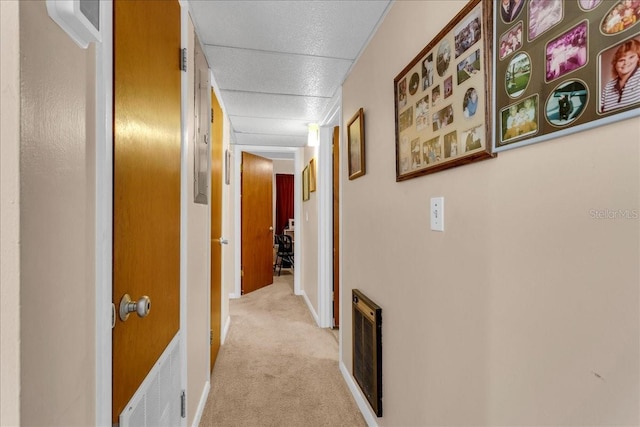 hallway featuring light carpet and a paneled ceiling