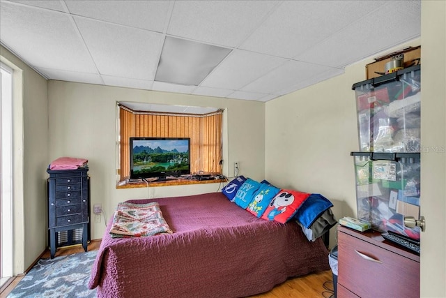 bedroom with a drop ceiling and hardwood / wood-style flooring