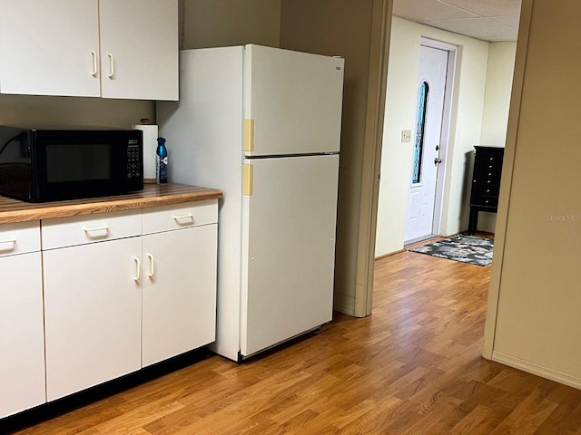 kitchen featuring white cabinetry, a drop ceiling, white fridge, and light wood-type flooring