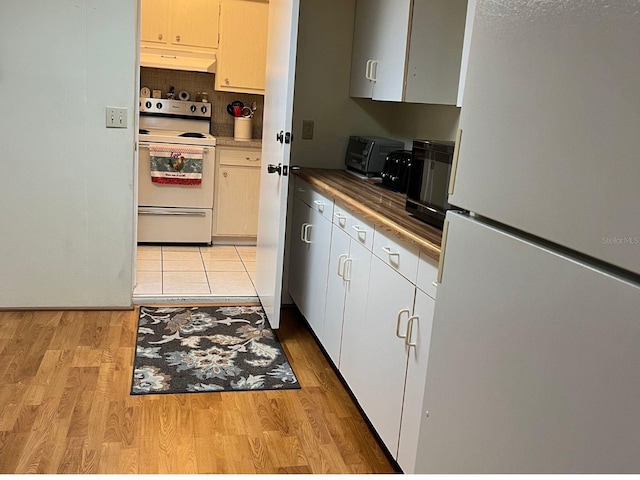 kitchen with decorative backsplash, light hardwood / wood-style floors, and white appliances