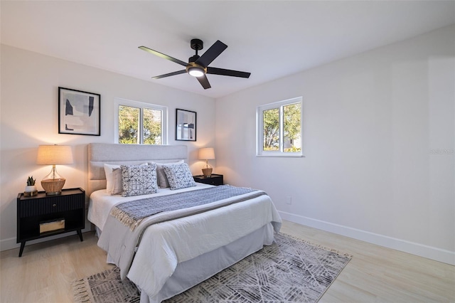 bedroom featuring multiple windows, ceiling fan, and light wood-type flooring