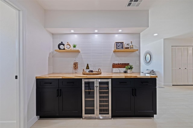 bar featuring butcher block counters, beverage cooler, and backsplash