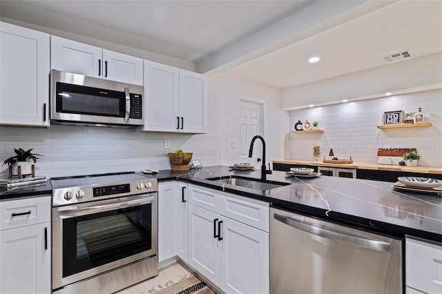 kitchen with stainless steel appliances, white cabinetry, sink, and tasteful backsplash