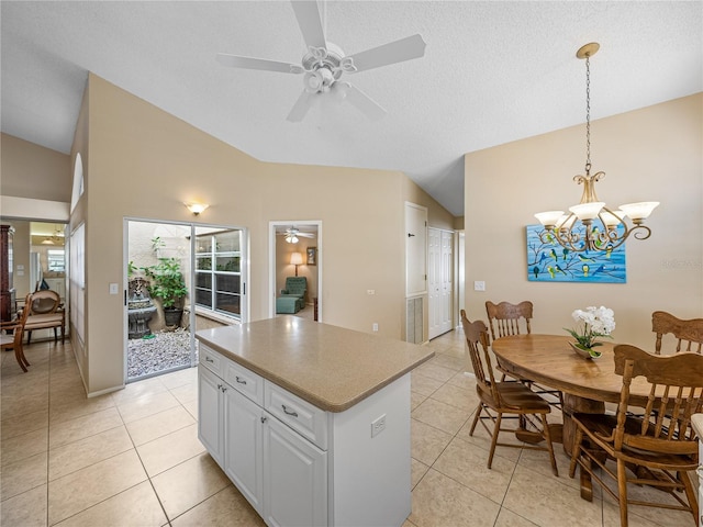 kitchen with light tile patterned floors, ceiling fan with notable chandelier, a kitchen island, and hanging light fixtures